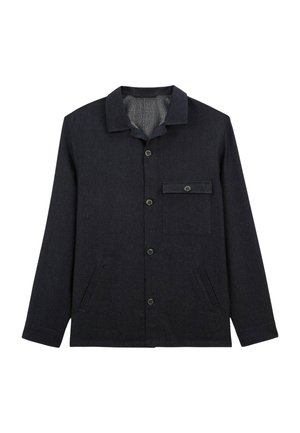 Veste boutonnée bleu foncé en tissu texturé, avec un col, une poche poitrine et des poches latérales. Les boutons sont ronds et sombres.