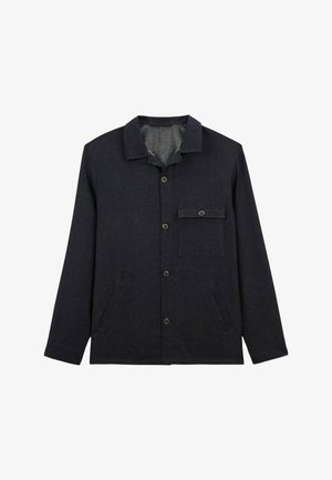 Veste boutonnée bleu foncé en tissu texturé, avec un col, une poche poitrine et des poches latérales. Les boutons sont ronds et sombres.
