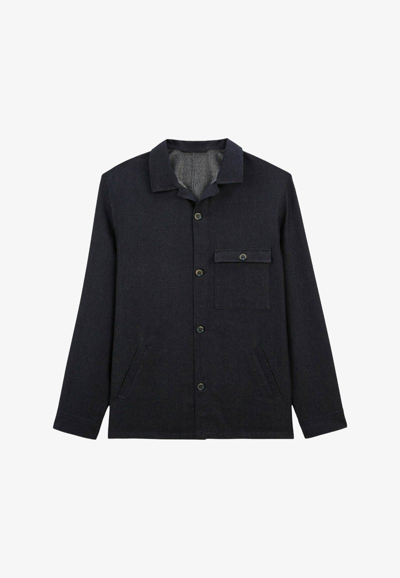 Veste boutonnée bleu foncé en tissu texturé, avec un col, une poche poitrine et des poches latérales. Les boutons sont ronds et sombres.