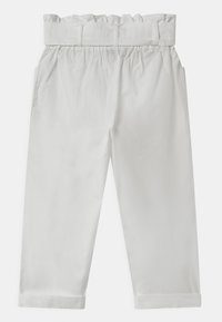 Bílé bavlněné kalhoty s nařaseným pasem, bočními kapsami a ohrnutými manžetami, které vykazují hladkou strukturu a čistý design.