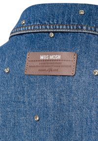 Denim overhemd met een gestructureerde kraag, voorzien van metalen studs en een bruine leren label met reliëftekst bij de nek.