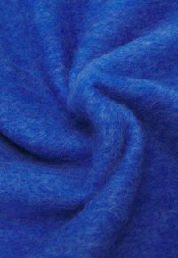 Tissu en feutre bleu vif avec une texture douce et duveteuse, présentant des plis lisses et une subtile profondeur de couleur à la surface.