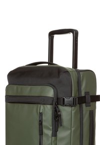 Grön duffelväska med svarts topp, blixtlåsförsedda framfickor, texturerad tyg och utdragbart handtag för enkel transport.