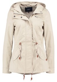 Veste légère beige avec capuche, poches latérales, cordons réglables et fermeture éclair. Présente des accents marron et une texture de tissu lisse.