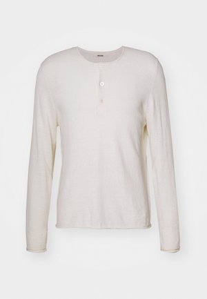 Maglietta henley a maniche lunghe di colore crema, realizzata in tessuto morbido, con scollo rotondo, tre bottoni sul davanti e orlo dritto.