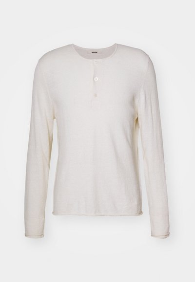 Langermet, kremfarget henley-skjorte laget av myk stoff, med rund hals, tre knapper foran og rett kant.