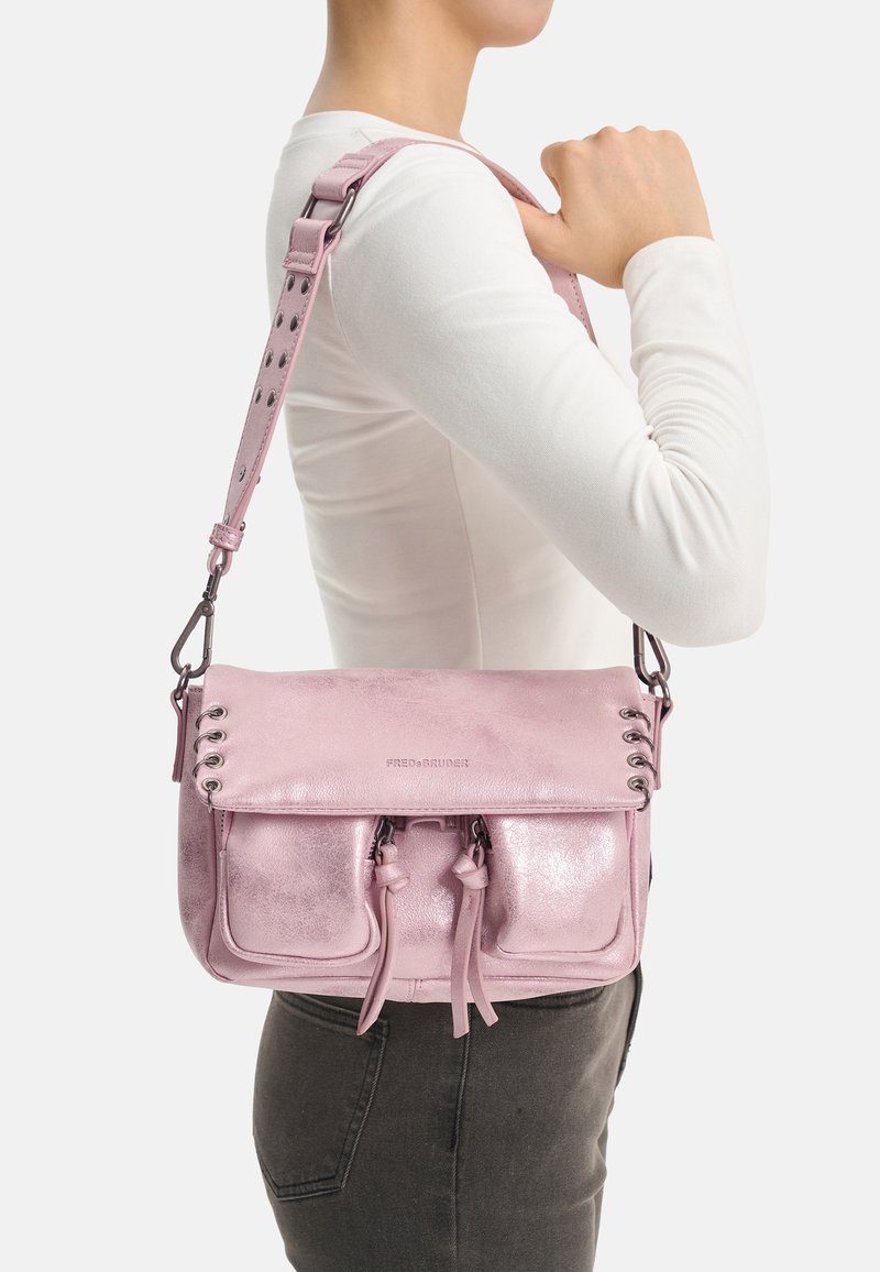 Sac à bandoulière en cuir rose avec une finition brillante, doté de deux poches avant, de détails à cordon et d'une bandoulière réglable cloutée.