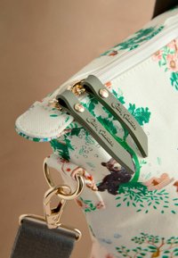 Borsa con motivo floreale realizzata in materiale canvas bianco, con dettagli verdi, hardware dorato e due zip con marchio inciso.