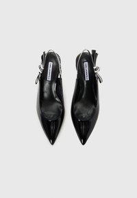Black patent leather slingback heels with pointed toes, featuring an adjustable strap and a subtle bow accent at the heel.