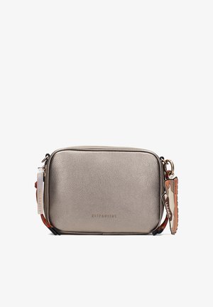 Bolso bandolera rectangular metálico plateado con acabado texturizado, correa con borde rojo y charm en forma de zapatilla sobre fondo blanco.