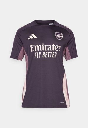 Mørkelilla fotballdrakt med kort erm, som har lyse rosa sidepaneler, brodert klubblogo og stor hvit sponsortekst.