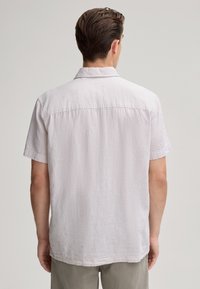 Camicia in lino grigia chiara a maniche corte con una texture morbida, colletto button-down e vestibilità rilassata. Presenta un reinserto sul retro.