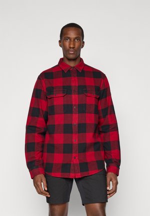 Rood-zwart geblokt flanellen shirt met knoopsluiting, twee borstzakken en lange mouwen, gecombineerd met zwarte shorts.