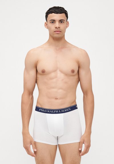 Beli bokserice z mornarsko modrim elastičnim pasom, na katerem je napisana oznaka "POLO RALPH LAUREN", narejene iz gladkega bombažnega materiala, z oprijetim dizajnom.