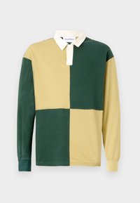 Camisa polo de manga larga con un diseño a rayas de colores en secciones verdes y amarillas, un cuello blanco y una textura de algodón suave.