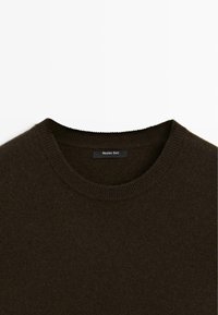 Maglione marrone di lana con colletto a coste. Etichetta visibile con il nome del marchio "Massimo Dutti" su uno sfondo uniforme.