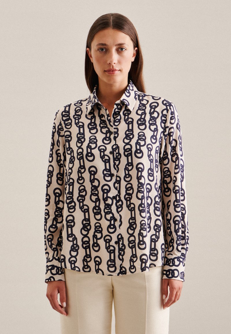 Blusa a maniche lunghe in tessuto crema con motivo a catena blu navy, colletto a bottoni e polsini con bottoni e bordi a contrasto.