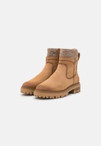 Tan enkellaarsjes met een gladde leren afwerking, een gebreide omranding in beige en een stevige, gemarmerde rubberen zool met diep profiel voor grip.