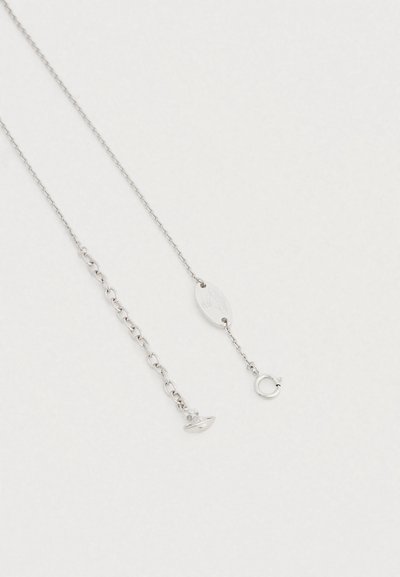 Strieborný retiazkový náhrdelník kombinujúci jemné a hrubšie očká, so zaobleným zapínaním a oválnou ceduľkou.