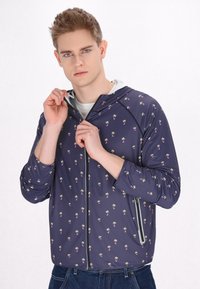 Giacca con cappuccio blu navy con un piccolo motivo di palme multicolore. Tessuto leggero, chiusura con zip frontale e polsini a coste. Dotata di tasche laterali.