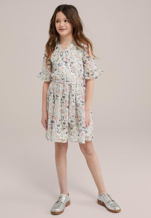 Blumenkleid mit kurzen Rüschärmeln, aus weichem Stoff, hellgrüner Hintergrund, rosa und lila Blumen, tailliert, kombiniert mit silbernen Schuhen.