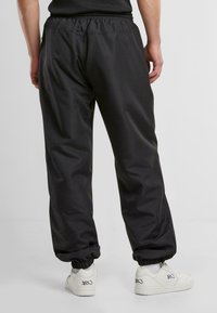 Sorte joggingbukser med elastisk talje og manchetter, lavet af glat stof, med sidelommer og en afslappet pasform.