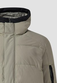 Gevoerde jas in licht taupe met een hoge kraag en zwarte accenten, voorzien van horizontale stiksels en zijzakken met rits.