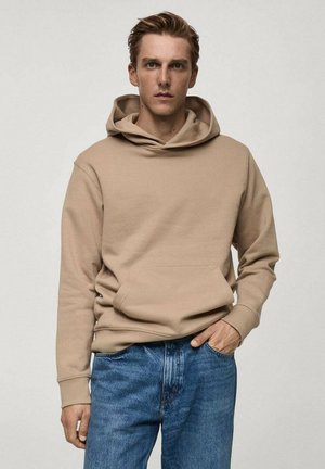 Felpa beige realizzata in tessuto morbido, con tasca centrale e cappuccio regolabile con cordino, abbinata a jeans blu in denim. Design semplice senza pattern visibili.