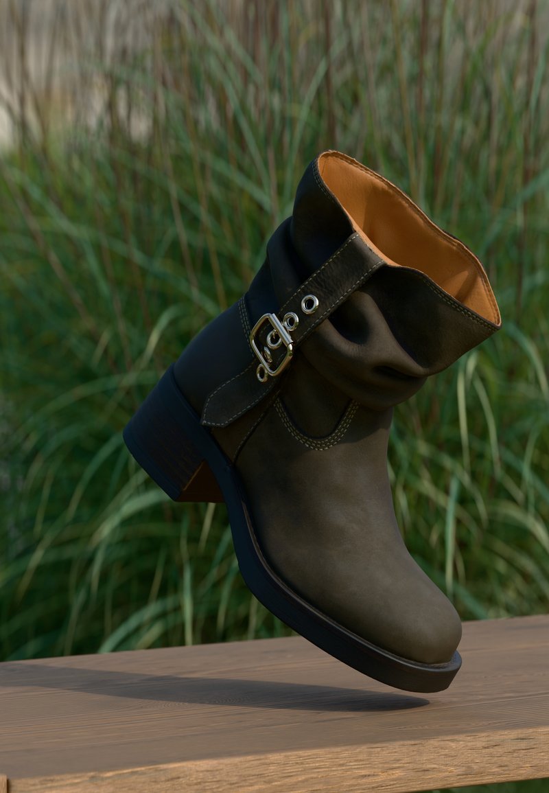 Bottine en cuir marron avec un col tombant, détail de boucle sur le côté et un talon empilé. L'intérieur présente une doublure orange contrastante.