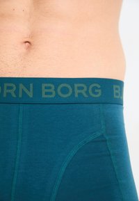 Τιρκουάζ ανδρικά σλιπ με φαρδύ σκούρο πράσινο λάστιχο που φέρει την επιγραφή "BJORN BORG". Λείος υφασμάτινος σχεδιασμός και εφαρμοστός στυλ με αντίθετη ραφή.