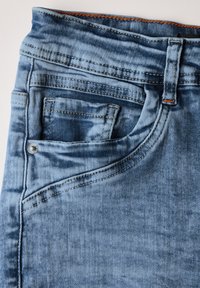 Jeans de mezclilla azul claro con un diseño de cinco bolsillos, costuras naranjas en contraste y una textura suave y desgastada, con un pequeño bolsillo para monedas.