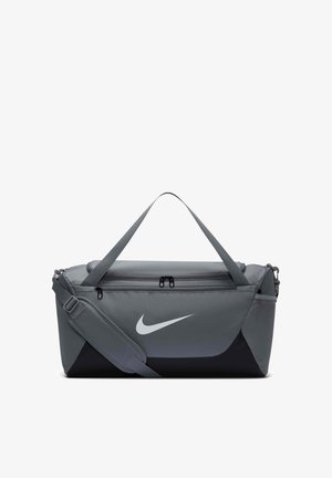 Sac de sport Nike gris et noir avec bandoulière, poignées, poche avant zippée et poche latérale en mesh.
