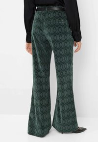 Pantaloni svasati verdi con motivo a fantasia, realizzati in tessuto strutturato, con un design discreto, una tasca posteriore e una cintura nera in vita.