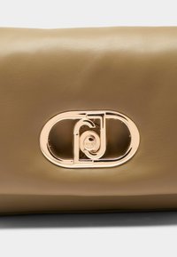 Beżowa skórzana torebka o gładkiej fakturze, z owalnym zapięciem w kolorze złotym oraz wytłaczanym logo.
