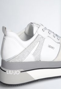 Baskets blanches avec un accent texturé argenté et une semelle en caoutchouc grise. Dotées de lacets, de détails de logo et d'un col rembourré pour le confort.