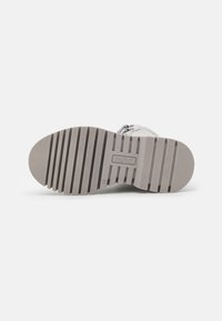 Gray rubber sole of a shoe with ridged pattern, featuring a logo and marker for size 36, surface texture is smooth with slight grooves.