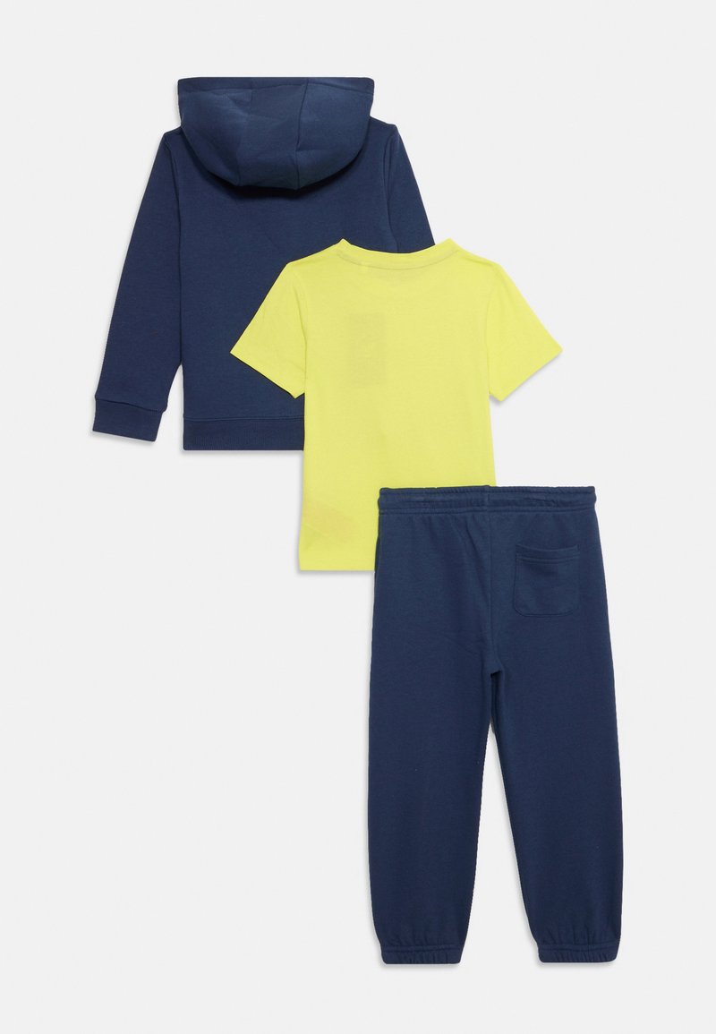 Felpa con cappuco blu navy, maglietta a maniche corte gialla brillante e pantaloni felpati blu navy. Tessuto morbido con polsini a coste e tasca sul retro dei pantaloni.