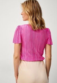 Plisseret kortærmet top i lys pink med lodrette striber og en cropped design. Stofserien ser let og tekstureret ud.