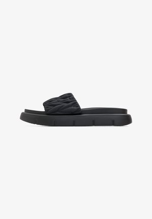 Zwarte slidesandalen met een gequilt bovendeel en een dikke, textuurrijke zool met groeven voor grip. Lichtgewicht en minimalistisch ontwerp.
