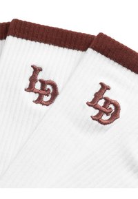 Șosete albe cu dungi și textură cu nervuri, având un manșon maro, cu inițiale brodate în maro. Concepute pentru confort și durabilitate.