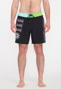 Bañador negro con una cinturilla multicolor que presenta tonos verdes y azul claro. Los pantalones cortos tienen patrones gráficos en blanco a lo largo de los lados.
