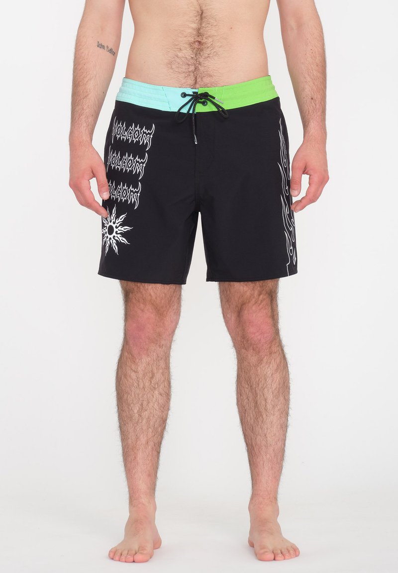 Bañador negro con una cinturilla multicolor que presenta tonos verdes y azul claro. Los pantalones cortos tienen patrones gráficos en blanco a lo largo de los lados.