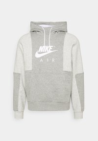 Tvåfärgad grå Nike Air hoodie med vita dragsko och framfickor, som har Nike-logotypen i vitt på bröstet.