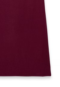 Mörkröd tygpanel med ren fåll, som ser slät och skrynkelfri ut, mot vit bakgrund på höger sida.