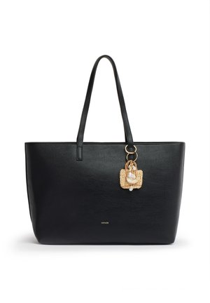 Sac cabas en cuir noir avec deux bretelles et un charm tissé beige décoratif avec des perles suspendu à un anneau doré.