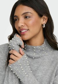 Grå strikkegenser med høy krage og perlepynt på kragen og ermene. Har ribbestrikkede mansjetter for en tettsittende design.