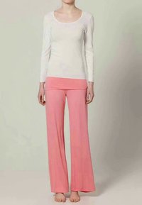 Dlhý rukáv, top s okrúhlym výstrihom v svetlej smotanovej farbe, skombinovaný s voľnými, vysokými nohavicami z mäkkej ružovej látky. Bez výrazných vzorov alebo akcentov.