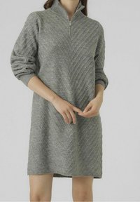 Robe tricotée grise avec un col à fermeture éclair à moitié, présentant un motif chevron texturé et des manches amples, arrivant à mi-cuisse.