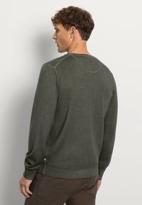 Grüner Strickpullover mit langen Ärmeln, runder Ausschnitt und geripptem Saum; zeichnet sich durch eine subtile Textur und seitliche Details in der Nähe des Saums aus.