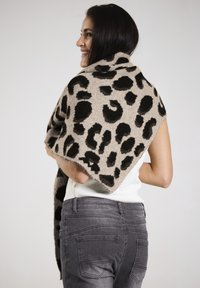 Beige shawl with bold black leopard spots, made from a soft material. The edges are finished cleanly, draped over the shoulders.